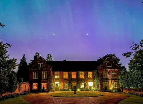 The south elevation framed by the Northern Lights in Spring 2024